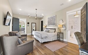 A bedroom with a bed, two armchairs, a rug, a lamp, and a painting on the wall. - Hobnob - Private Pool - Golf Cart (Santa Rosa Beach)