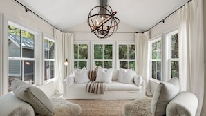A room with a large windowed bay, a white sofa, two armchairs, and a unique ceiling light fixture. - Hobnob - Private Pool - Golf Cart (Santa Rosa Beach)