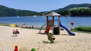 A beach with a playground, including slides and swings, and a view of a lake with boats. - diemelseeholiday Romantic Apartment with Balcony in the Sauerland near Willingen & Winterberg (Diemelsee)