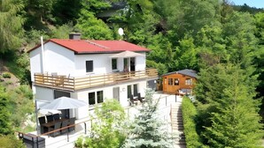 A two-story house with a red roof, a balcony, and a small wooden cabin. - diemelseeholiday Romantic Apartment with Balcony in the Sauerland near Willingen & Winterberg (Diemelsee)