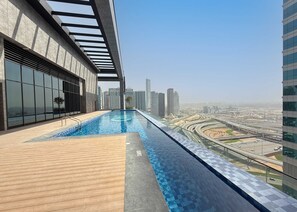 Ein Pool auf dem Dach mit Blick auf die Stadt, moderne Architektur und ein klarer Himmel.