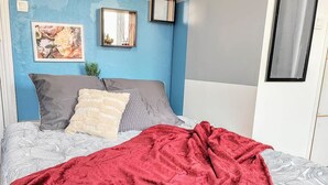 A bedroom with a bed, a red blanket, and a blue wall with floral patterns. - Manoir des Lumi res 5 ch Terrasse Wifi 5 sdb (Roubaix)