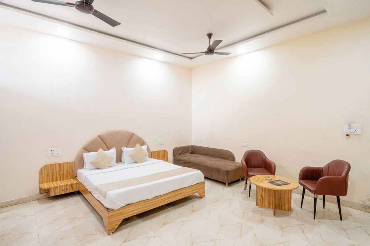 Une chambre à coucher comprenant un lit, deux chaises, un canapé, une petite table et deux ventilateurs de plafond.