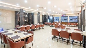 A spacious dining area with multiple tables and chairs, a marble floor, and large windows. - Hotel Entry Point (Raipur)