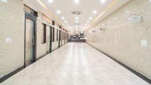 A long, well-lit hallway with marble walls and floors, leading to a staircase. - Hotel Entry Point (Raipur)