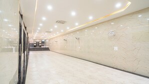 A spacious corridor with marble walls and a polished floor, leading to a staircase. - Hotel Entry Point (Raipur)