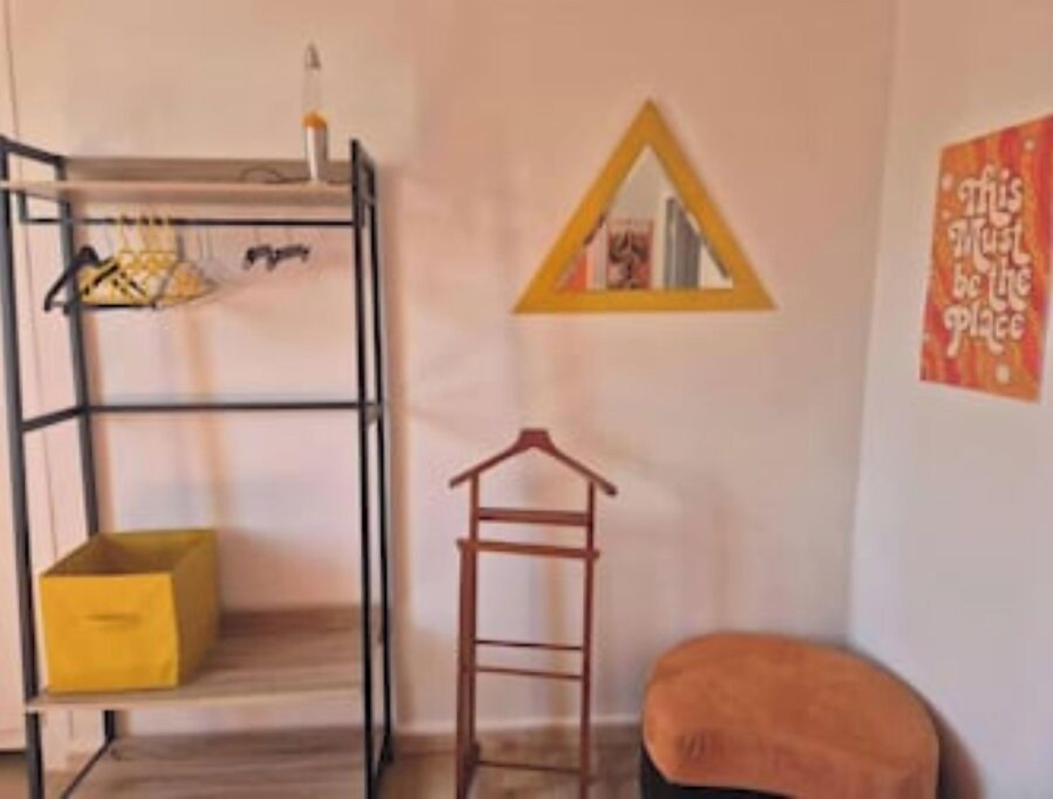 Una cama litera con escalera, un taburete de madera y un caja de almacenamiento amarilla.