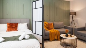 A modern hotel room with a bed, two sofas, a coffee table, and a floor lamp. - Central Leeds Apartment Near Station - Sleeps 6 (Leeds)