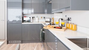 A modern kitchen with grey cabinets, a wooden countertop, and a stainless steel sink. - Central Leeds Apartment Near Station - Sleeps 6 (Leeds)