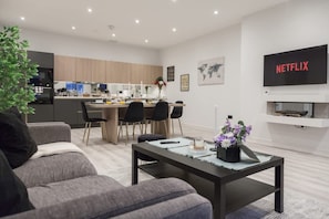 A modern living room with a sofa, a coffee table, and a TV displaying 'NETFLIX'. - Grand Central Leeds Apartment Near Train Station (Leeds)