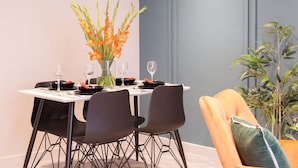 A dining table set with plates, glasses, and a vase of flowers. - Somers Suites Apartments-central-high Spec-sleep 4 (Leeds)