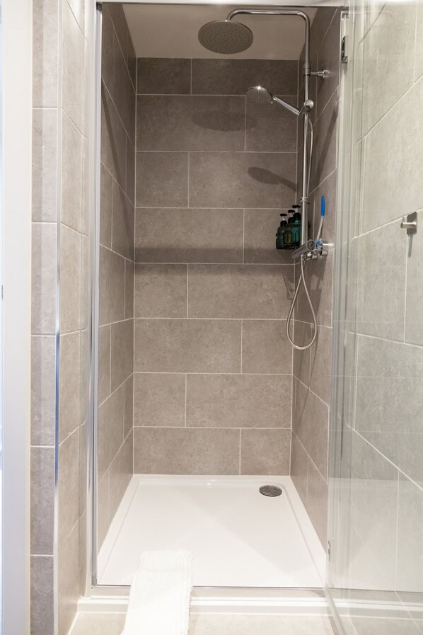 A walk-in shower with a glass door, tiled walls, and a handheld showerhead. - Somers Suites Apartments-central-high Spec-sleep 4 (Leeds)
