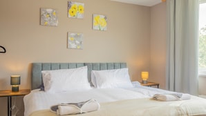Een hotelkamer met een bed, twee nachtkastjes met lampen en bloemistisch kunstwerk aan de muur.