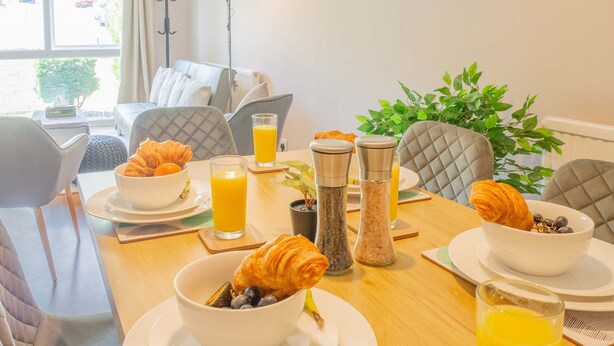Een ontbijt met croissants, bosbessen en sinaasappelsap op een houten tafel.