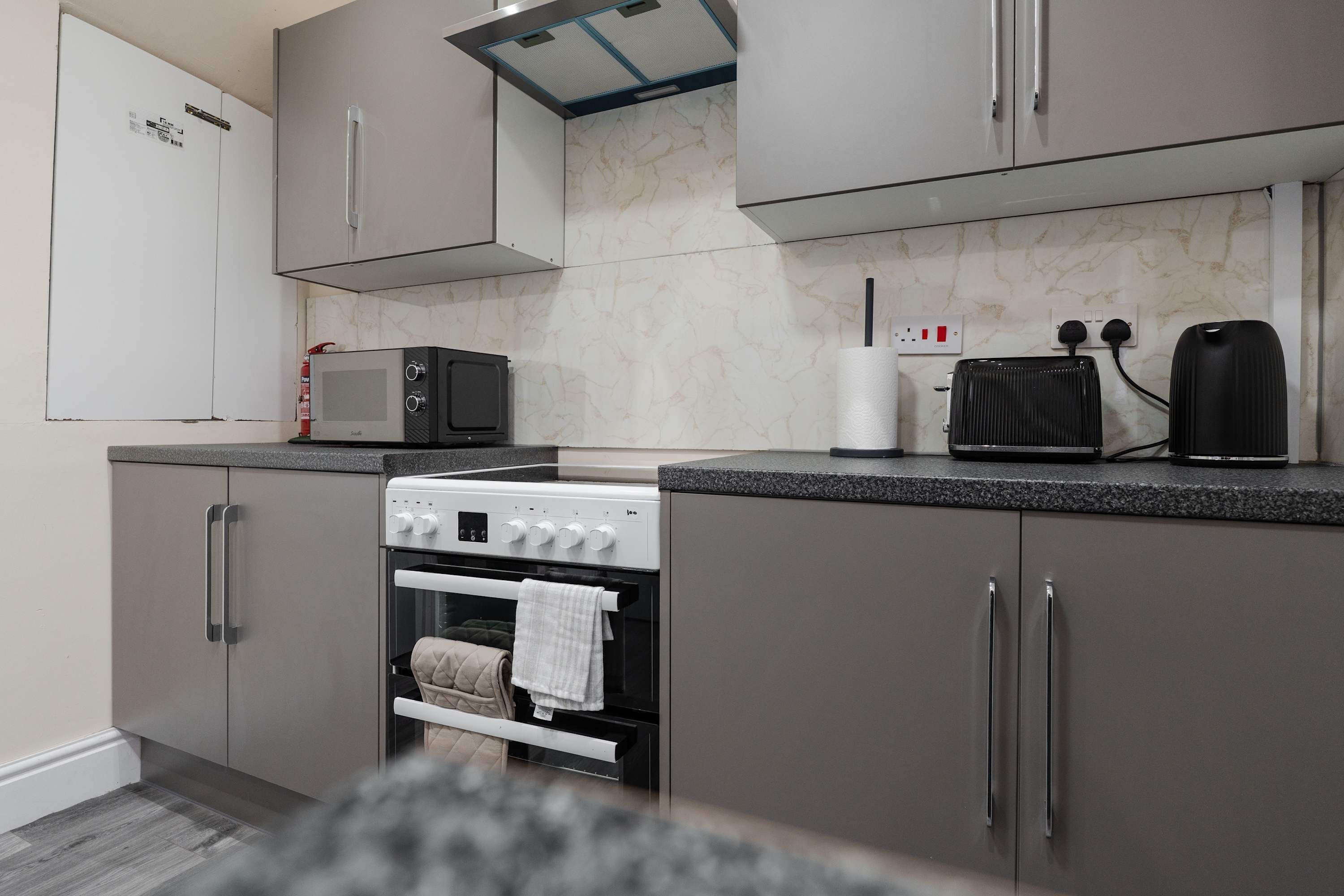 A kitchen with a microwave, toaster, oven, and cabinets.