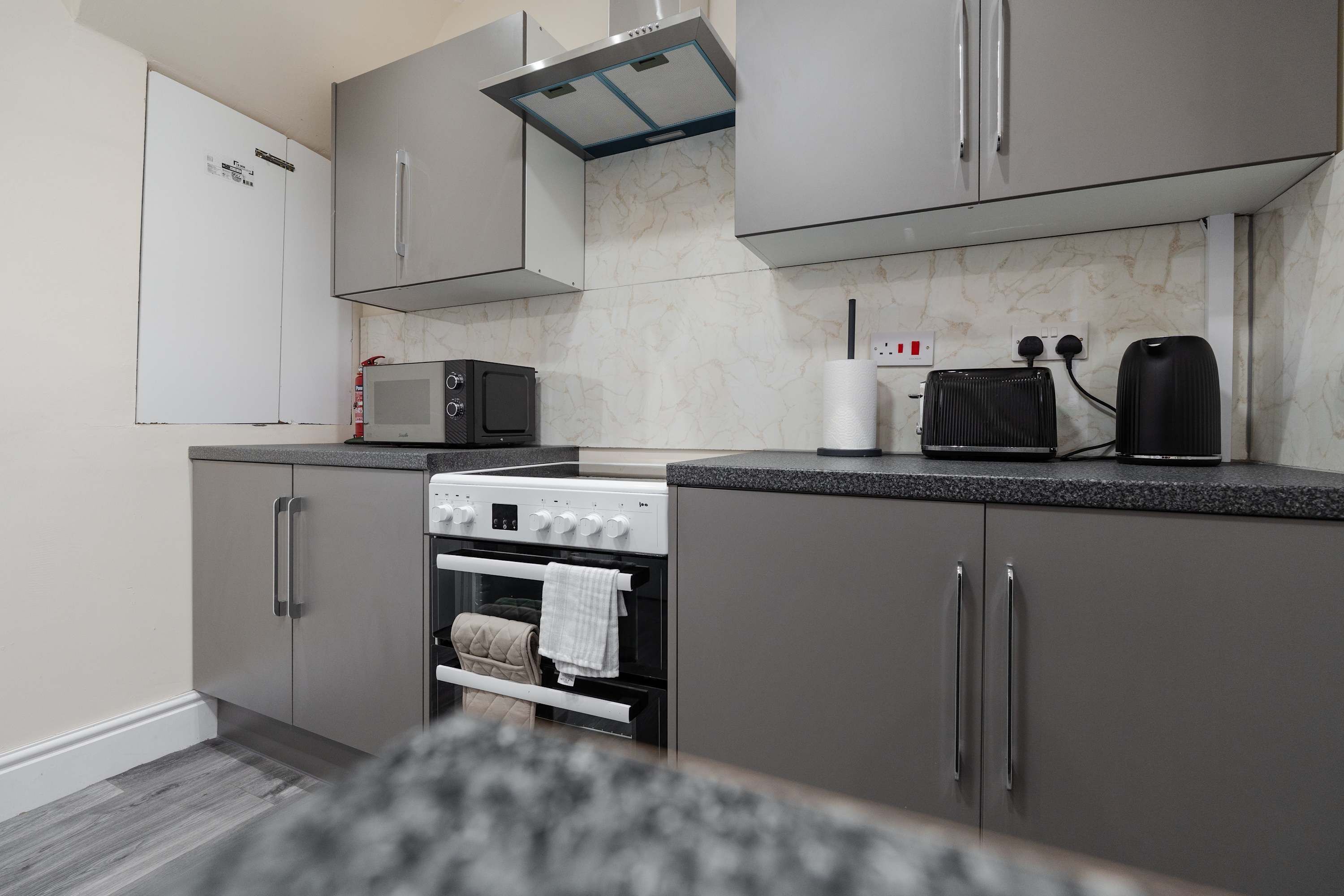 A compact kitchen with a built-in oven, microwave, and a kettle.