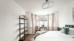 A bedroom with a bed, a desk, a chair, a bookshelf, and a window with curtains. - 3 Bed House Near Epping Forest Greater London (London)