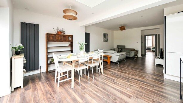 A spacious living area with a dining table, chairs, a sofa, and a kitchen area. - 3 Bed House Near Epping Forest Greater London (London)