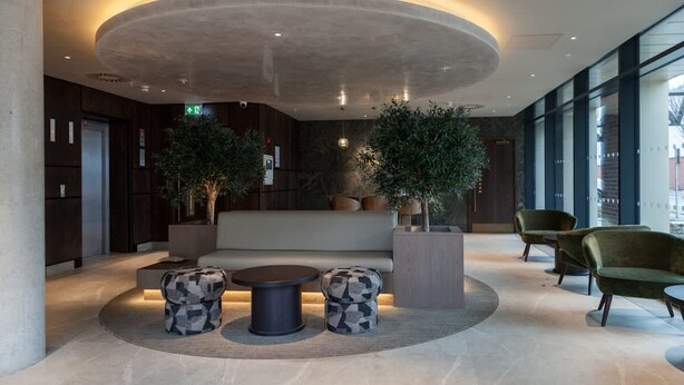 Een moderne lobby met een rond plafond, een zithoek en potplanten.