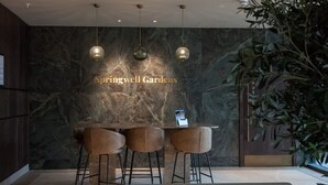 Een bar met een marmeren wand, drie barkrukken en hangende吊灯.