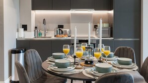 Een moderne keuken met donkere kastjes, een eettafel gedekt met borden, glazen en een koffiezetapparaat.