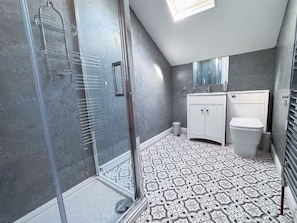 A bathroom with a shower, a toilet, a sink, and a mirror. - 6 Bedroom Victorian Townhouse in Central Harrogate (Harrogate)