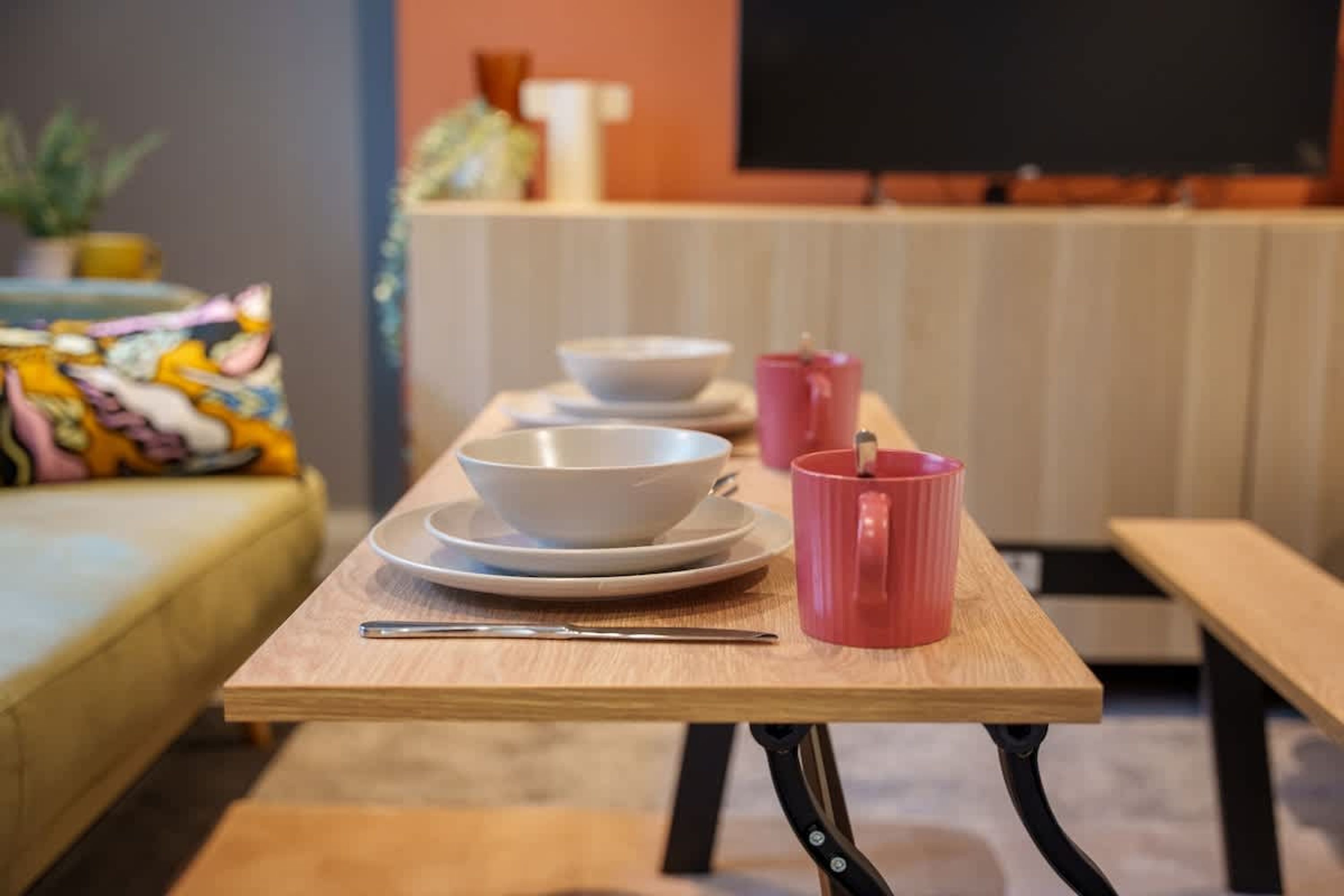 A dining table with white bowls, plates, and a pink mug.