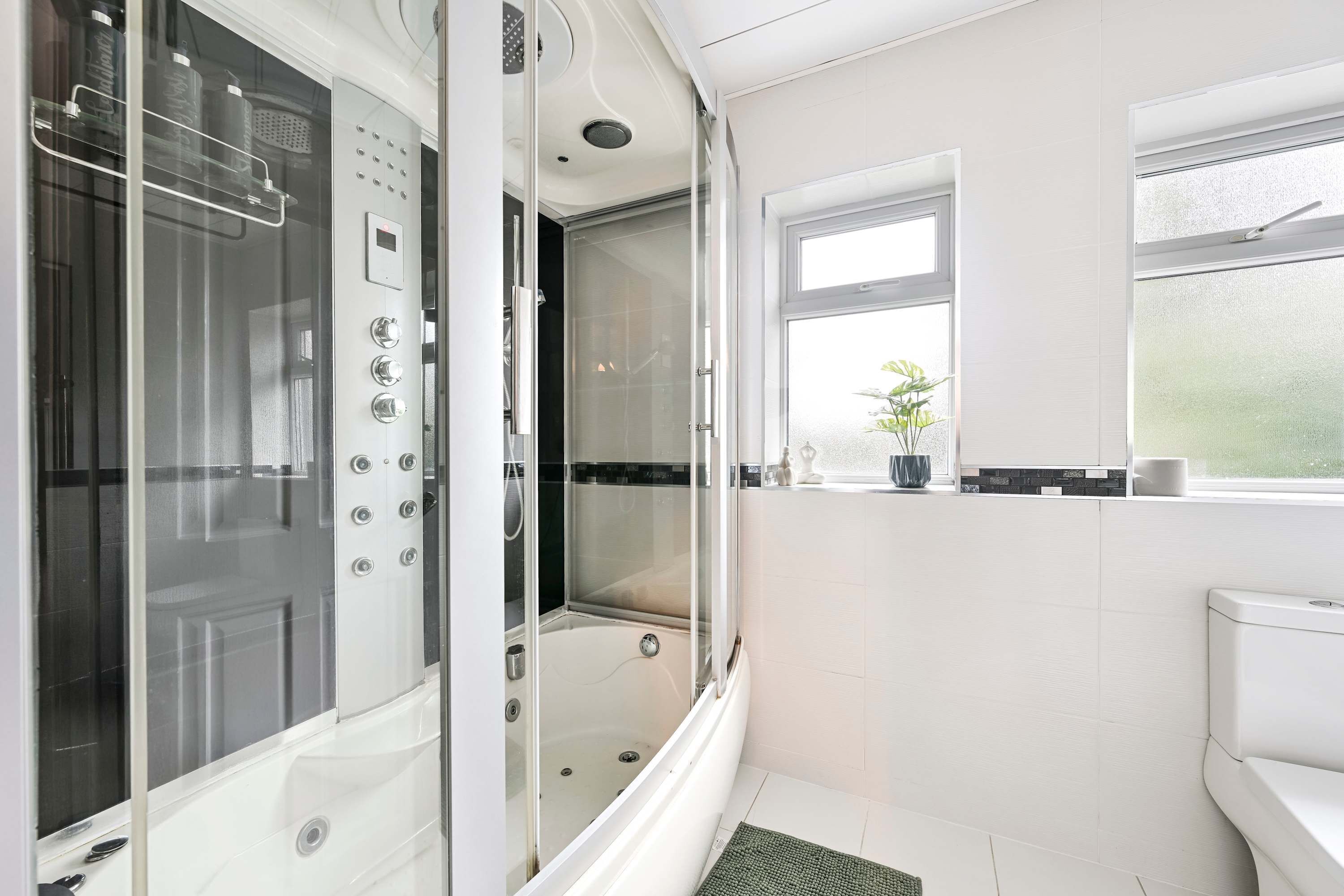 Une salle de bain moderne avec une douche à parois de verre, des toilettes et une fenêtre.