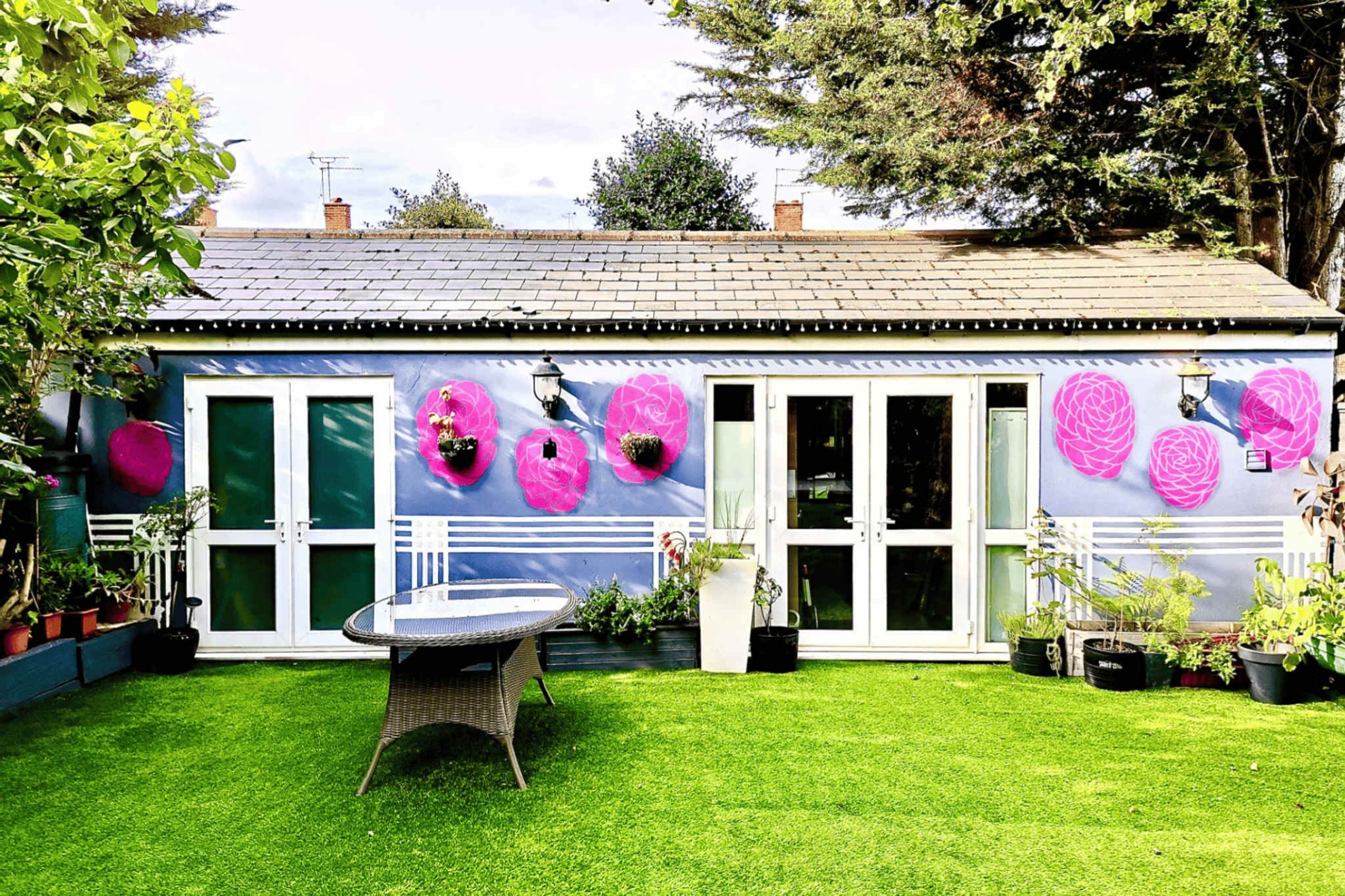 A house with a garden, a patio table, and potted plants.