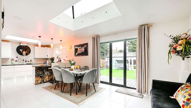 A modern interior with a dining area, kitchen, and living space, featuring a skylight and large windows. - Windsor 5-bed House - Stroll to Castle - Sleeps 13 (Windsor)