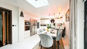A modern kitchen with a dining area, a skylight, and a view of the adjacent living space. - Windsor 5-bed House - Stroll to Castle - Sleeps 13 (Windsor)