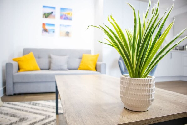 A modern living room with a grey sofa, yellow pillows, a wooden coffee table, and a potted plant.