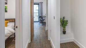 A hallway with a bed, a desk, and a potted plant. - Brighton Penthouse Apartment Near Beach & Kemptown (Brighton)