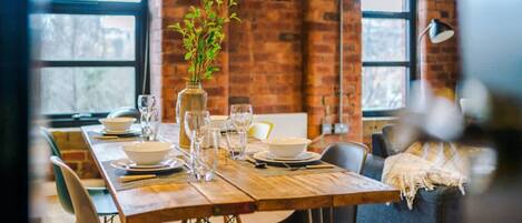 A dining table set with plates, glasses, and a vase with greenery.