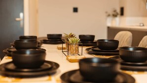 Une table à manger dressée avec des bols et des assiettes noirs, une petite plante et un chandelier.