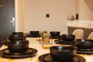 Une table à manger dressée avec des bols et des assiettes noirs, une petite plante et un chandelier.