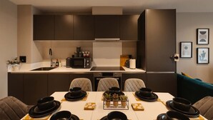 Une cuisine moderne avec des meubles de couleur sombre, un four à micro-ondes et un coin repas avec une table dressée pour quatre personnes.