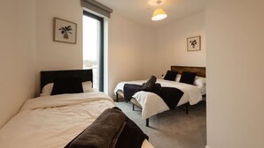 Une chambre d’hôtel avec deux lits, une grande fenêtre et un luminaire au plafond.