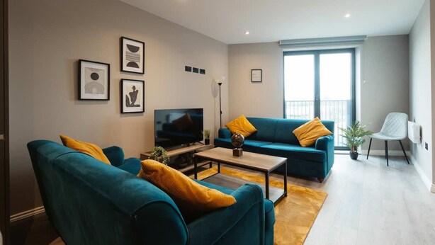 Un salon moderne avec des canapés de couleur turquoise, un téléviseur à écran plat et des œuvres d’art accrochées aux murs.