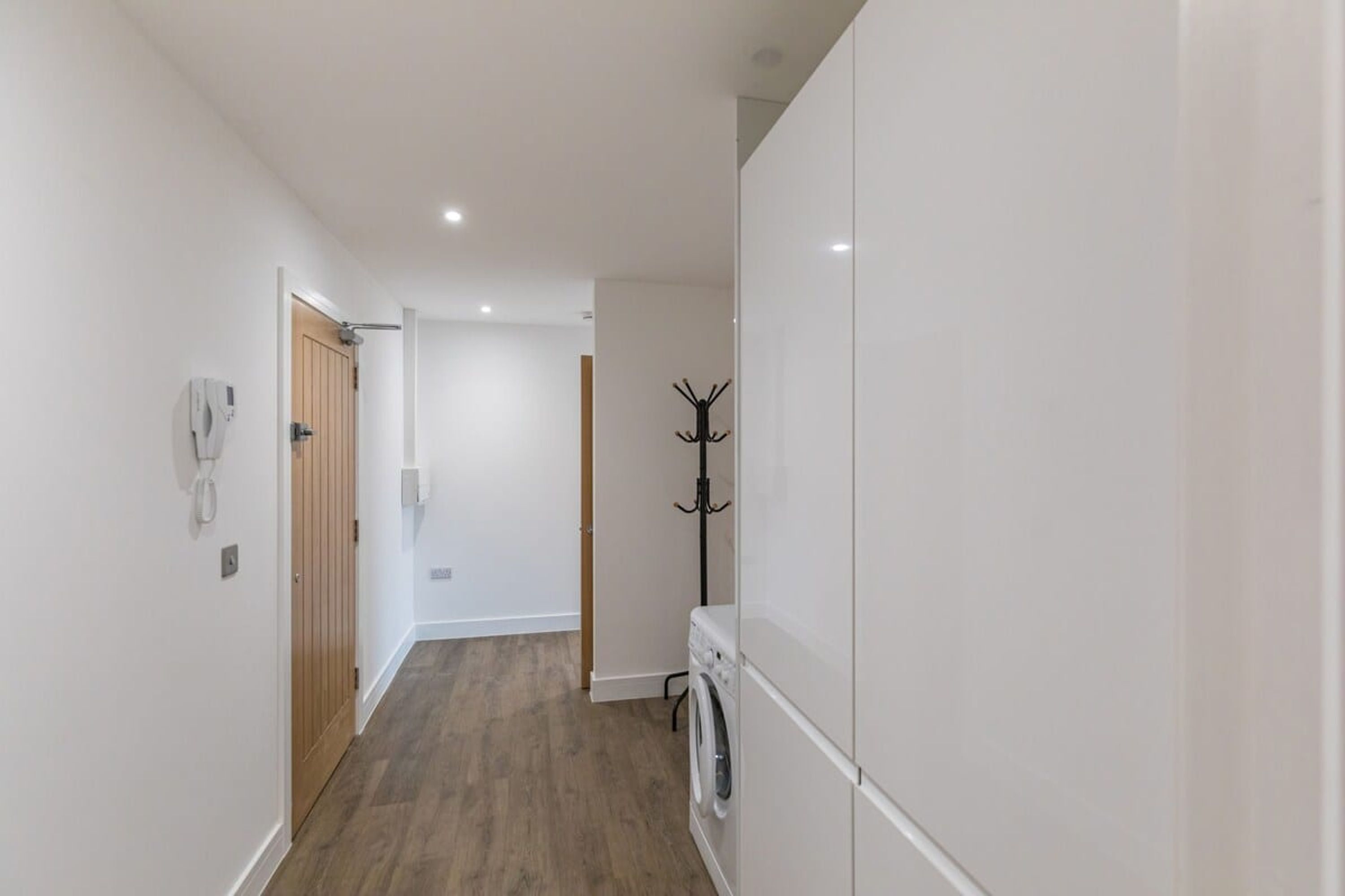 A hallway with a wooden door, a coat rack, and a washing machine.