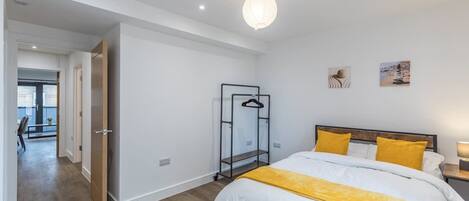 Quarto com cama, guarda-roupa, cabideiro e vista para uma varanda.