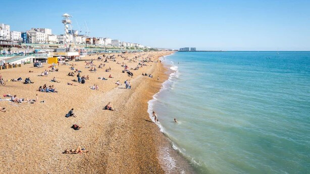 A beach with people sunbathing and swimming, a pier with buildings, and a clear sky. - Seafront Penthouse w/ Balcony Central Brighton (Brighton)
