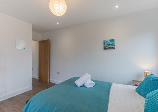 A bedroom with a bed, a painting, a wooden door, and a light fixture. - Seafront Penthouse w/ Balcony Central Brighton (Brighton)