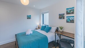 A bedroom with a bed, bedside table, lamp, and artwork on the wall. - Seafront Penthouse w/ Balcony Central Brighton (Brighton)