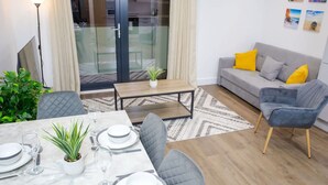 A modern living room with a grey sofa, a dining table set for four, and a small coffee table. - Seafront Penthouse w/ Balcony Central Brighton (Brighton)