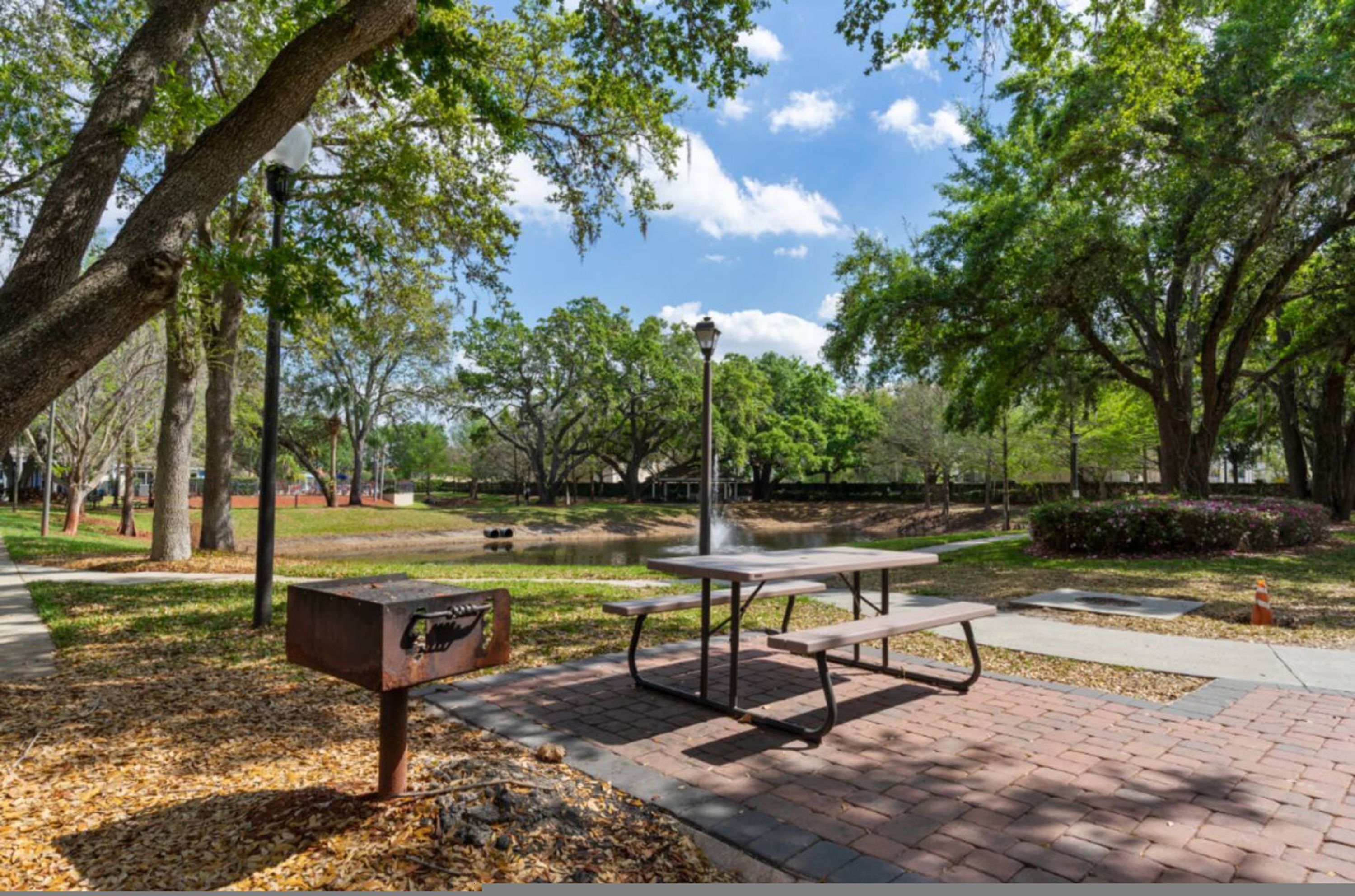 A park with picnic tables, a bench, and a trash can.