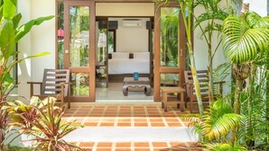 A room with a bed, a small table, and a chair, surrounded by plants and a tiled floor. - EASY TIME VILLA by MARALEINA (Koh Samui)