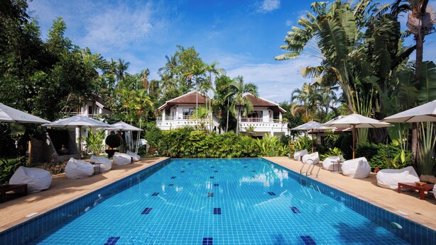 A swimming pool with tiled blue surface, surrounded by lounge chairs and umbrellas, with a building in the background. - EASY TIME VILLA by MARALEINA (Koh Samui)