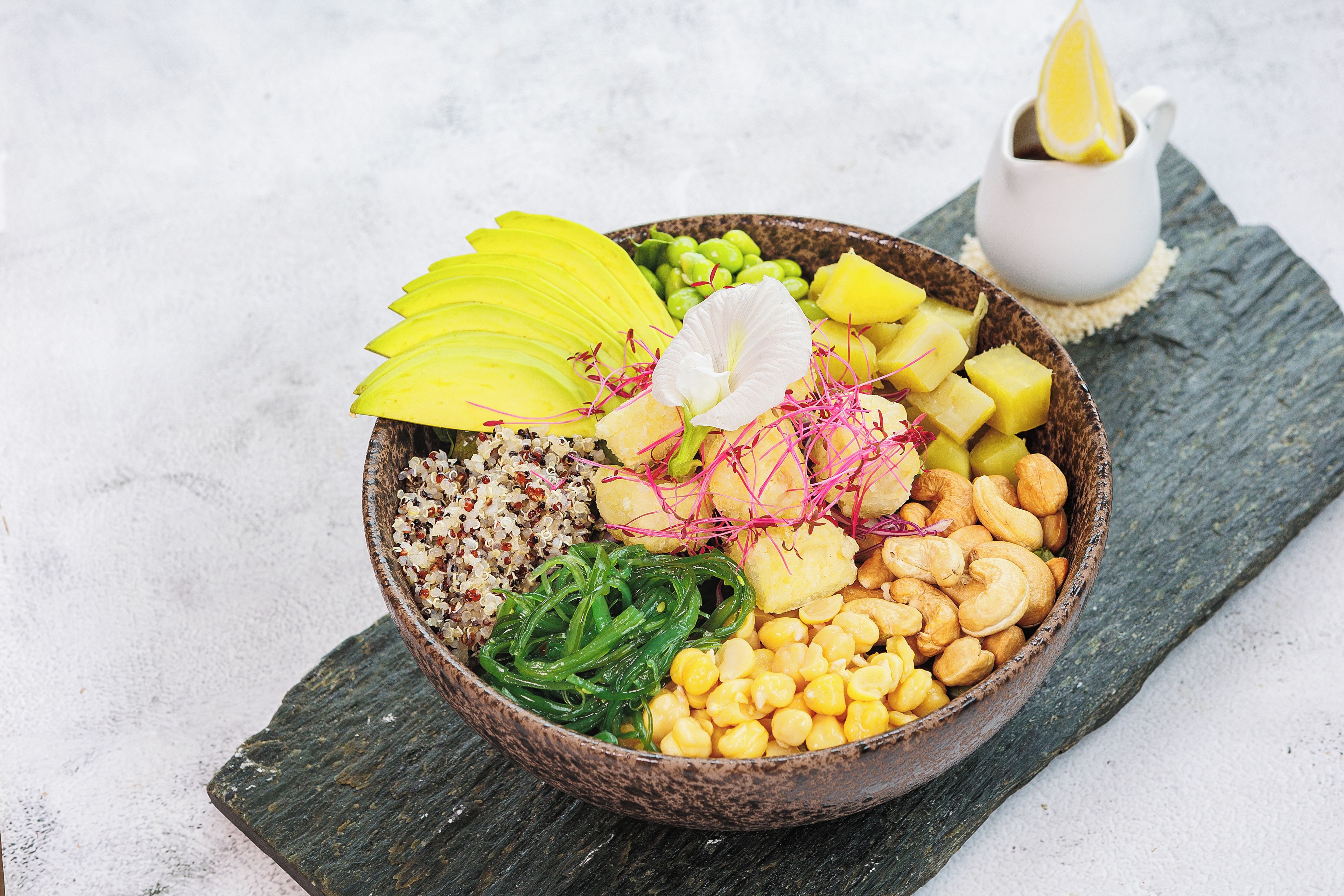 Un tazón con frutas y nueces variadas sobre una tabla de madera rústica.