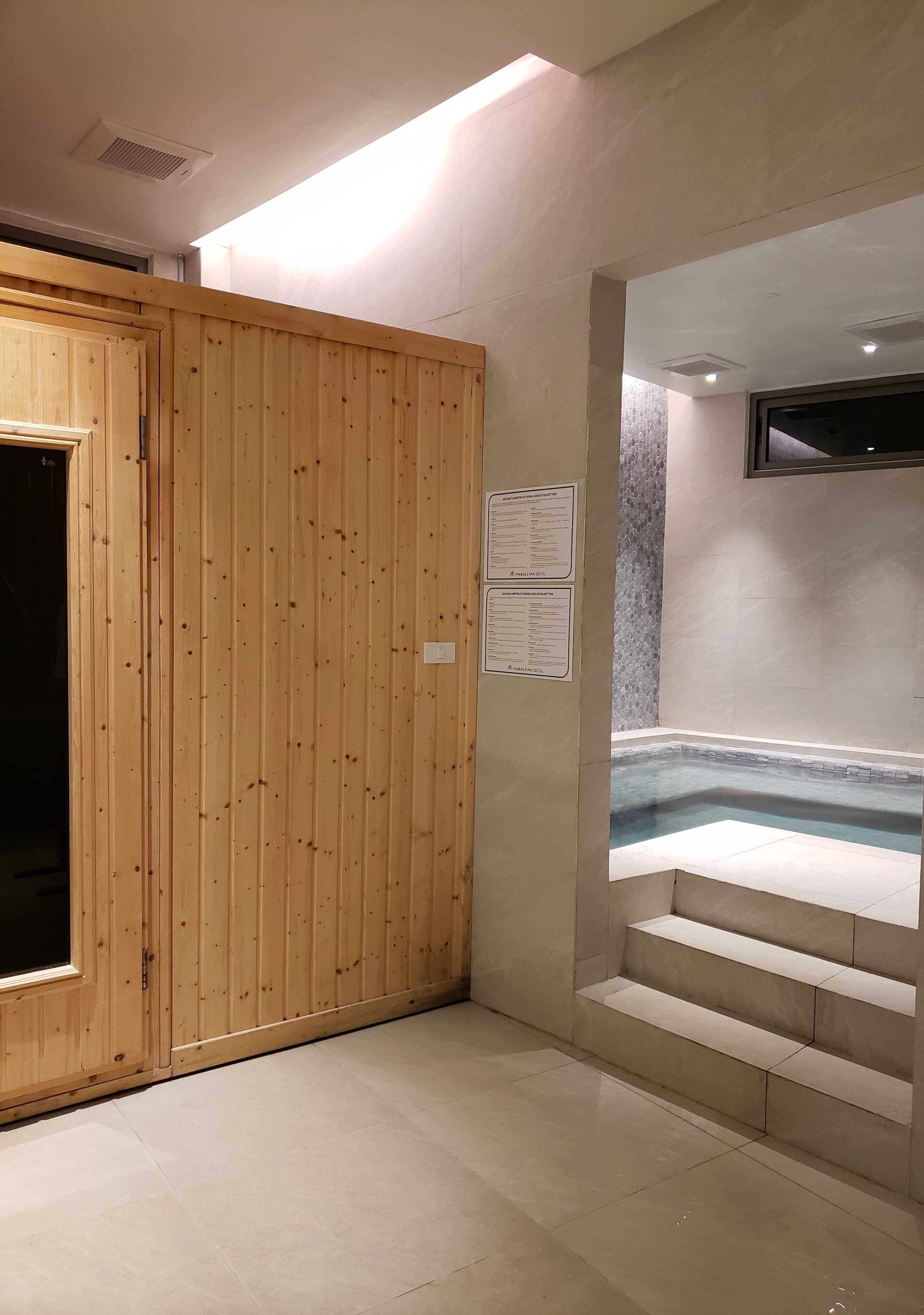 A spa area with a wooden wall, a hot tub, and a set of stairs leading to it.
